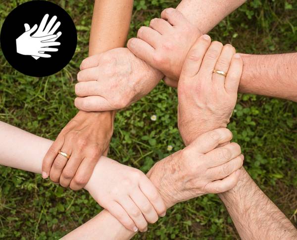 Piktogramm Gebärdenhände - Hände halten sich an den Handgelenken im Kreis. Im Hintergrund Rasen.