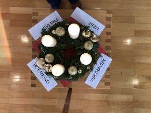Adventskranz umringt von den Worten Liebe, Vertrauen, Hoffnung und Frieden.